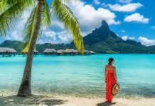 Polynésie française | 2023, année record ? Bora Bora luxury hotel vacation tourist woman relaxing by ocean beach with view of Mt Otemanu in Tahiti, Frenc Polynesia. High End resort with overwater bungalows villas @ credit Depositphotos
