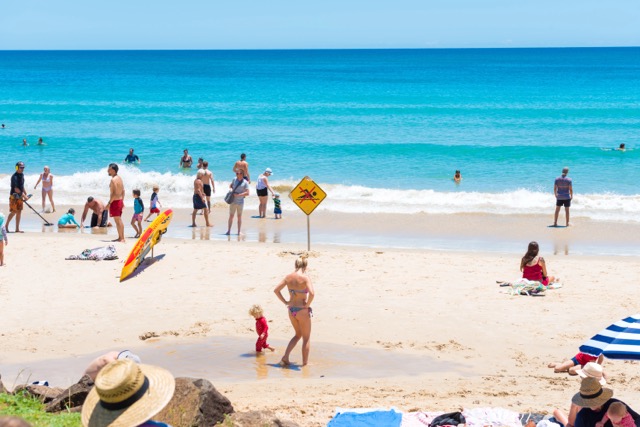 Byron Bay, NSW, Australia- January 3, 2018: People enjoying the sunny weather on the beach at Byron Bay, a popular destination with beaches and coastal trails on the North Coast of NSW, Australia.
