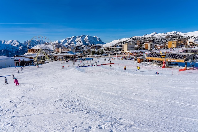 Alpe D'Huez, FRANCE - 01.01.2022: Famous ski resort in French Alps, France, Europe. Skiers skiing on the mountain, ski lift, family sports weekend, holidays in the snow mountains concept. Winter times