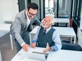 Senior boss happy for good online work result of young male businessman.