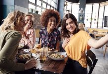 F&B d’hôtel | Finis les menus figés, le all-day-dining, les buffets et concepts dépassés : la restauration d’hôtel se réinvente ! Four Young Female Friends Meeting For Drinks And Food Posing For Selfie In Restaurant