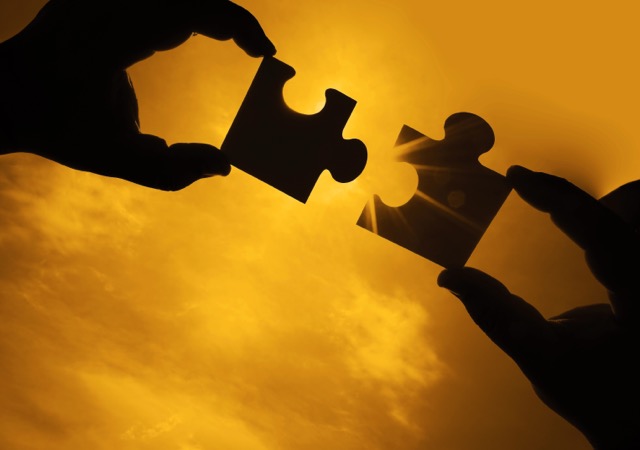 two hands trying to connect couple puzzle piece with sunset background. Jigsaw alone wooden puzzle against sun rays. one part of whole. symbol of association and connection. business strategy.