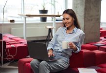 Point de droit | Télétravail : la Cour de cassation confirme le droit aux titres-restaurant pour tous les salariés Cheerful young woman with teacup in hand looking at computer monitor while sitting on chair in comfortable coworking space